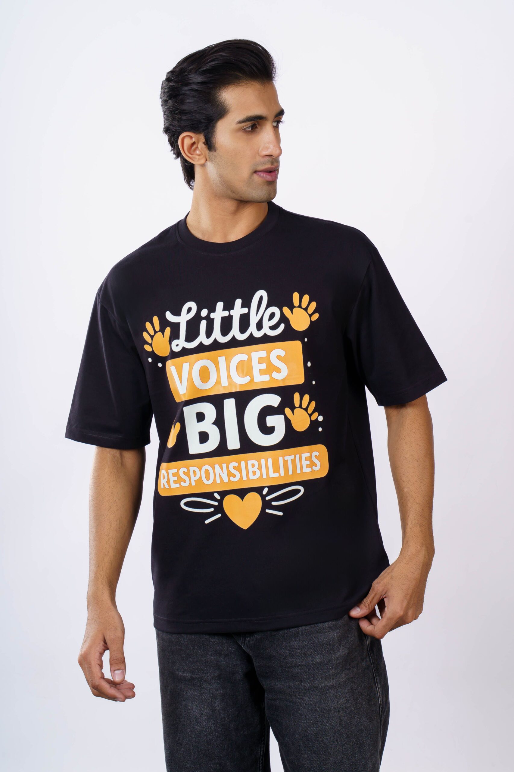South Asian man in oversized black T-shirt featuring a positive message, shot indoors.